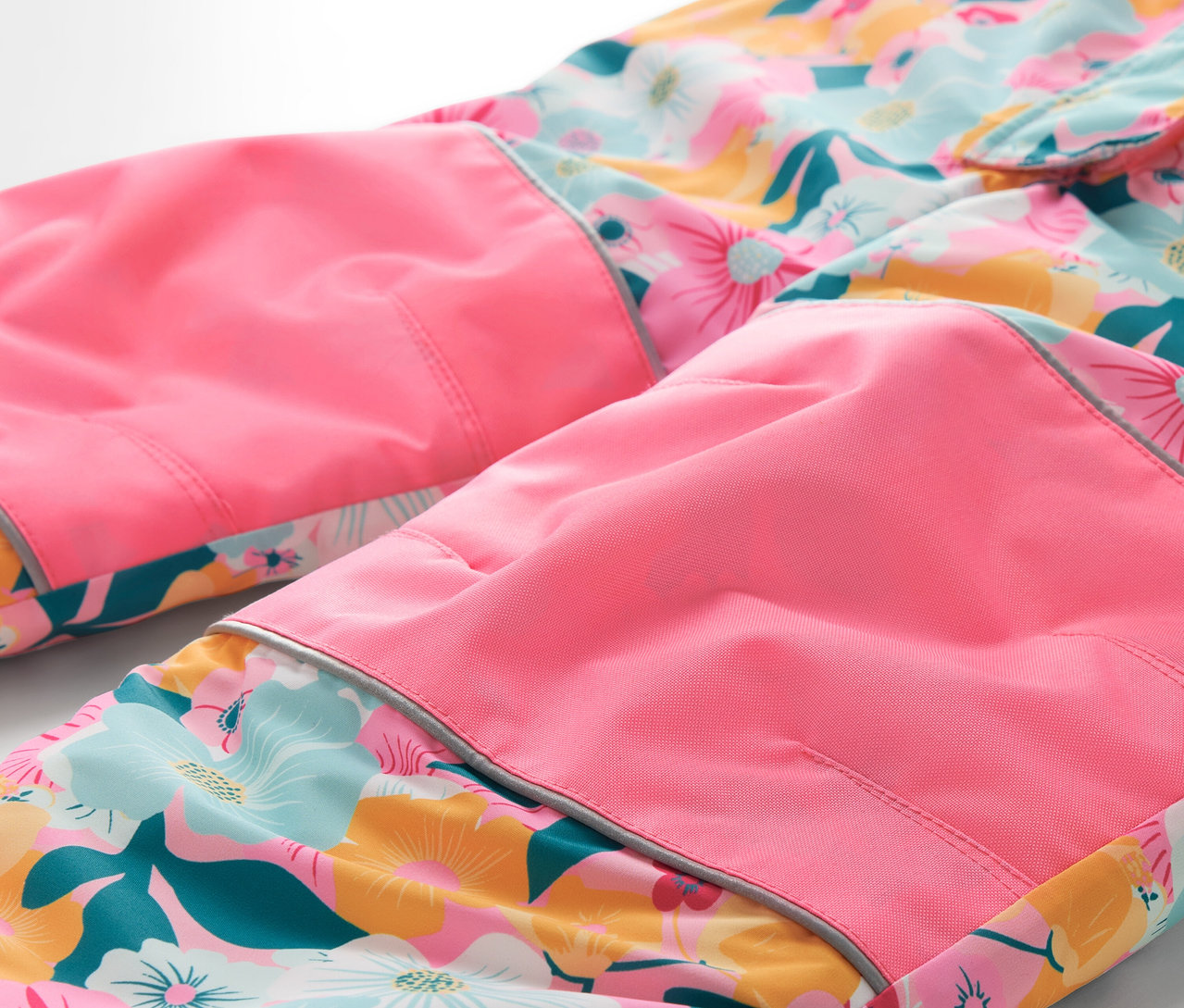 Detail einer geblümten Hose mit pinkfarbenen Knien.