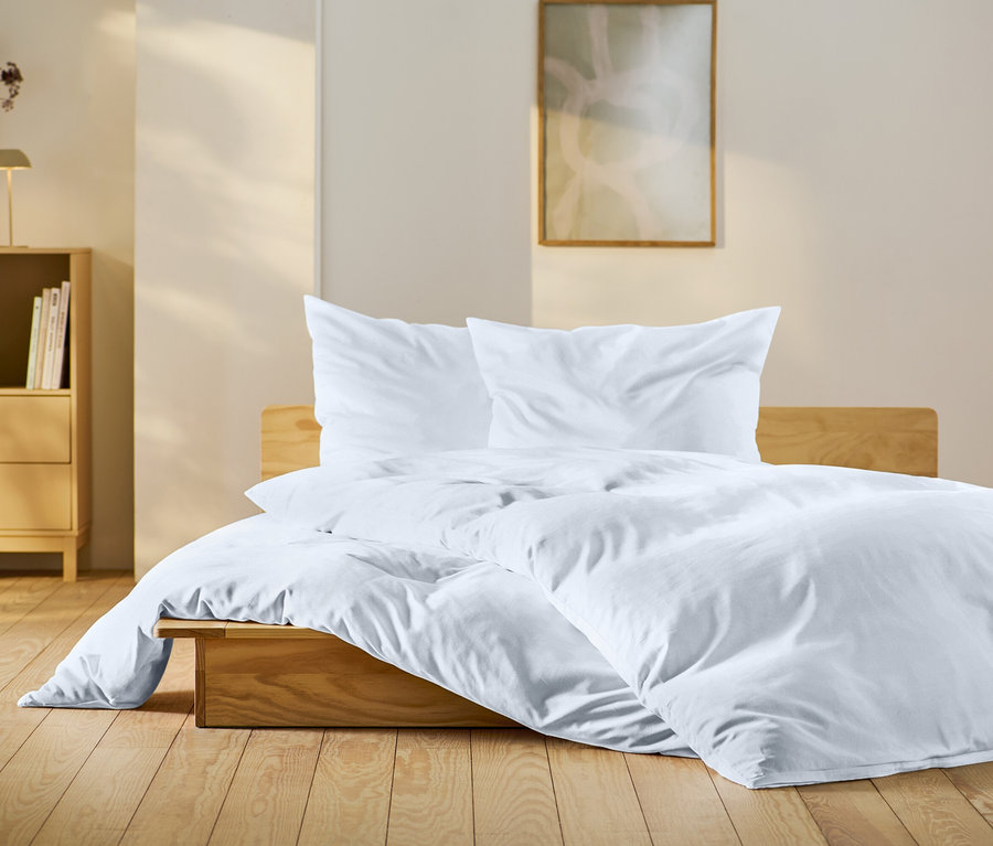 Schlafzimmer mit Holzbett mit weißer Bettwäsche, hölzernem Nachttisch und Dekorationen.