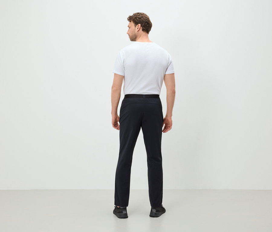 Mann von hinten trägt ein weißes T-Shirt, eine schwarze Hose und schwarze Schuhe.