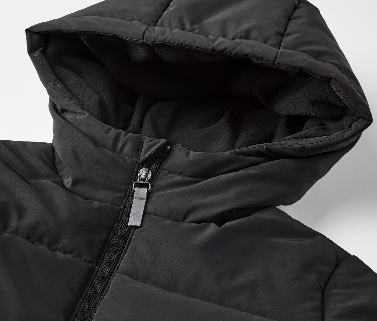 Detailaufnahme einer schwarzen Kinder-Steppjacke mit reflektierenden Elementen.