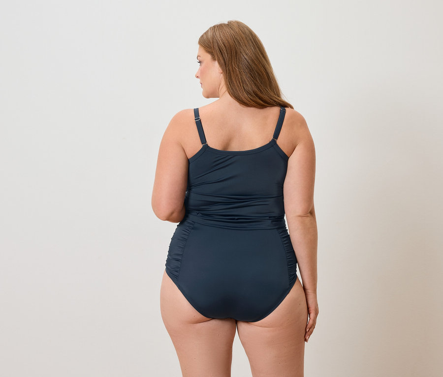 Rückansicht einer Frau mit langen braunen Haaren, die einen marineblauen Badeanzug trägt.