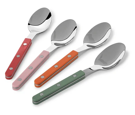 Vier Löffel mit roten, rosa, orangefarbenen und grünen Griffen liegen diagonal auf weißem Grund.