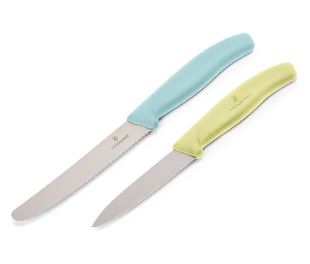 Zwei Victorinox Messer liegen diagonal auf einem weißen Hintergrund. Das obere Messer hat einen hellblauen Griff und eine gezackte Klinge, das untere Messer hat einen hellgelben Griff und eine glatte Klinge.