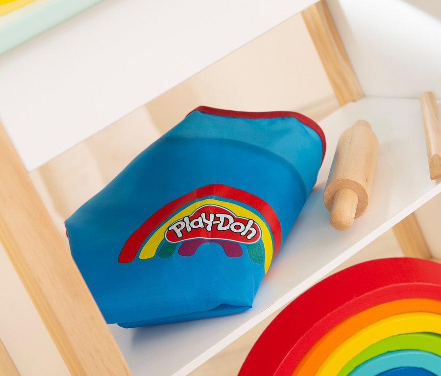 Auf einem Regal liegen eine blaue Play-Doh-Tasche, ein Holzroller und ein Regenbogen.