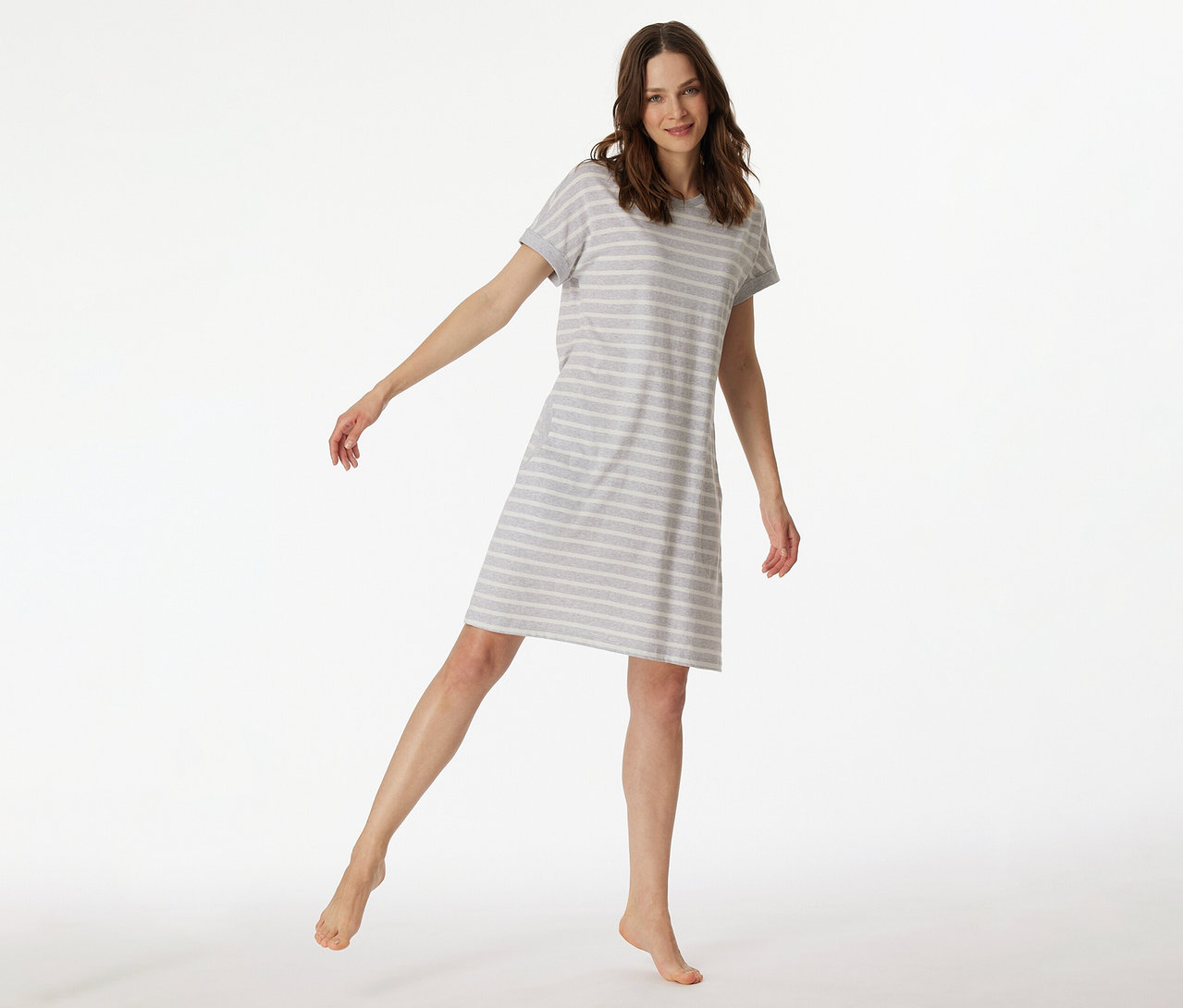 Frau in einem gestreiften SCHIESSER Kurzarm-Sleepshirt, die ein Bein anhebt.