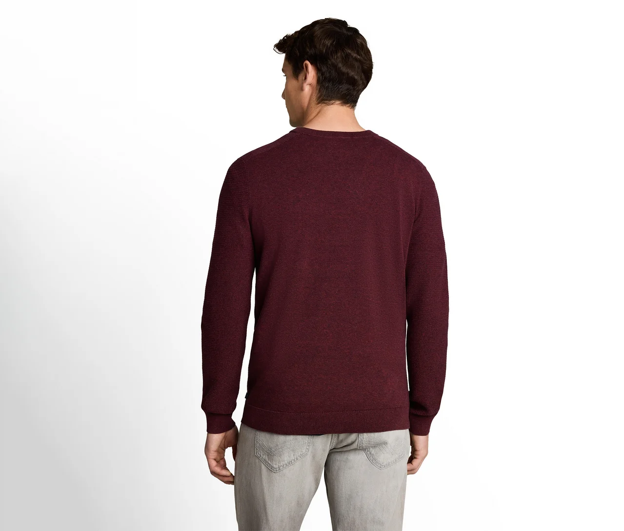 Mann von hinten, trägt einen bordeauxroten Langarmpullover und hellgraue Hosen.