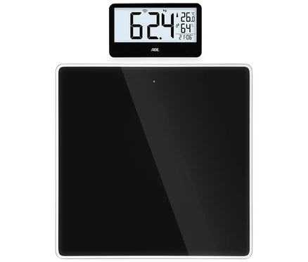 Schwarze digitale Personenwaage mit separatem Display, das 62,4 kg, 26,0 °C, 64 % Luftfeuchtigkeit und 21:06 Uhr anzeigt.