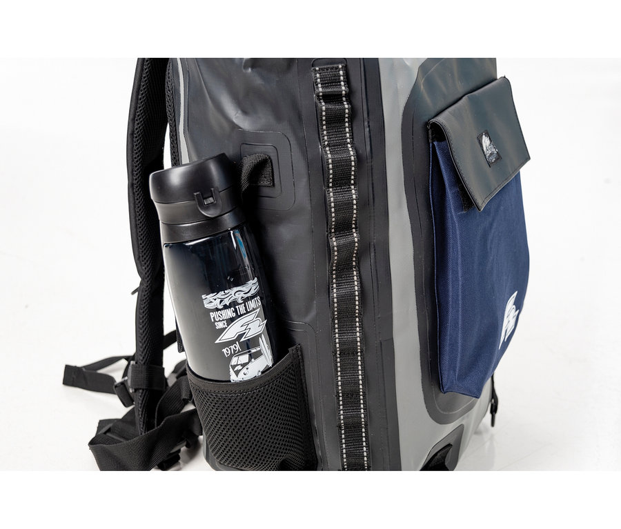 Eine schwarze Wasserflasche steckt in der Netztasche eines grauen Rucksacks mit blauer Tasche.