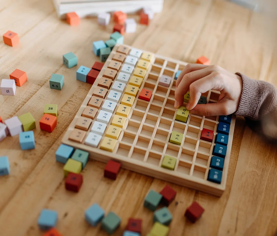 Kind spielt mit einem hölzernen small foot Rechen-Set »Educate« mit bunten Würfeln auf einem Holztisch.