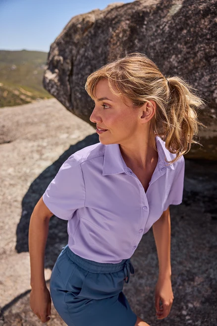 Frau trägt eine Outdoorbluse und blaue Funktionsrockshorts.