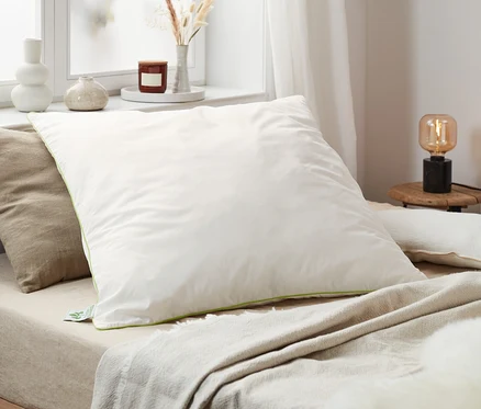 Auf einem Bett liegen irisette® greenline Federkopfkissen in verschiedenen Größen.