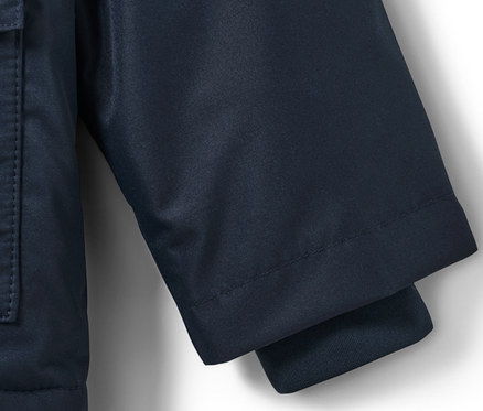 Detail einer Kinder-Thermo-Regenjacke mit Hund, der Ärmel und eine Tasche zeigt.