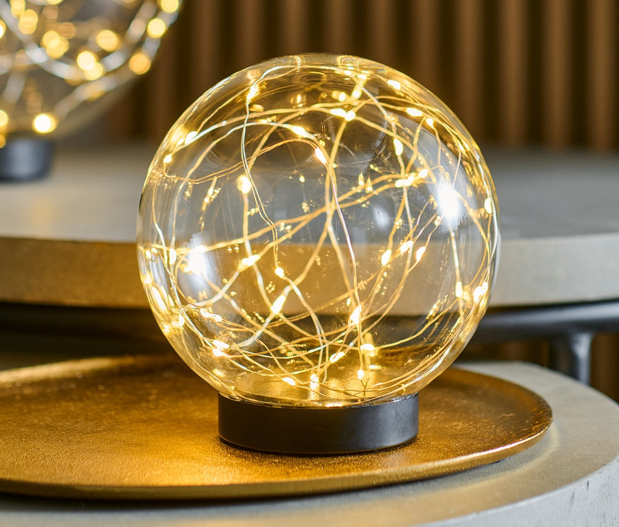 Zwei LED-Glaskugeln, je ca. 15 cm Durchmesser, stehen auf grauen Tischen.