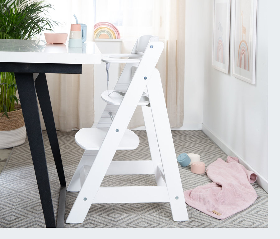 Weißer roba Treppenhochstuhl »Sit Up Flex« steht in einer Ecke des Zimmers neben einem Tisch.