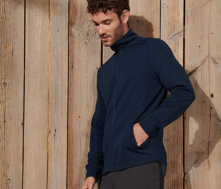 Mann trägt eine dunkelblaue Funktionsjacke und Shorts.