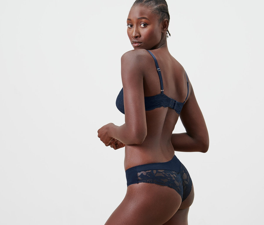 Frau posiert in blauem BH und 2 Brazilslips.