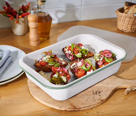 Gebackene Süßkartoffeln mit Tomaten, Zwiebeln und Feta-Käse in einer großen Emaille-Auflaufform mit Deckel.
