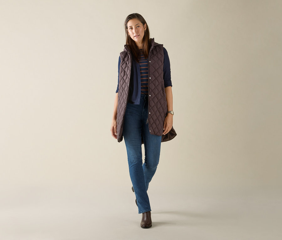 Frau trägt eine lange Steppweste mit Kapuze, dunkelbraun.