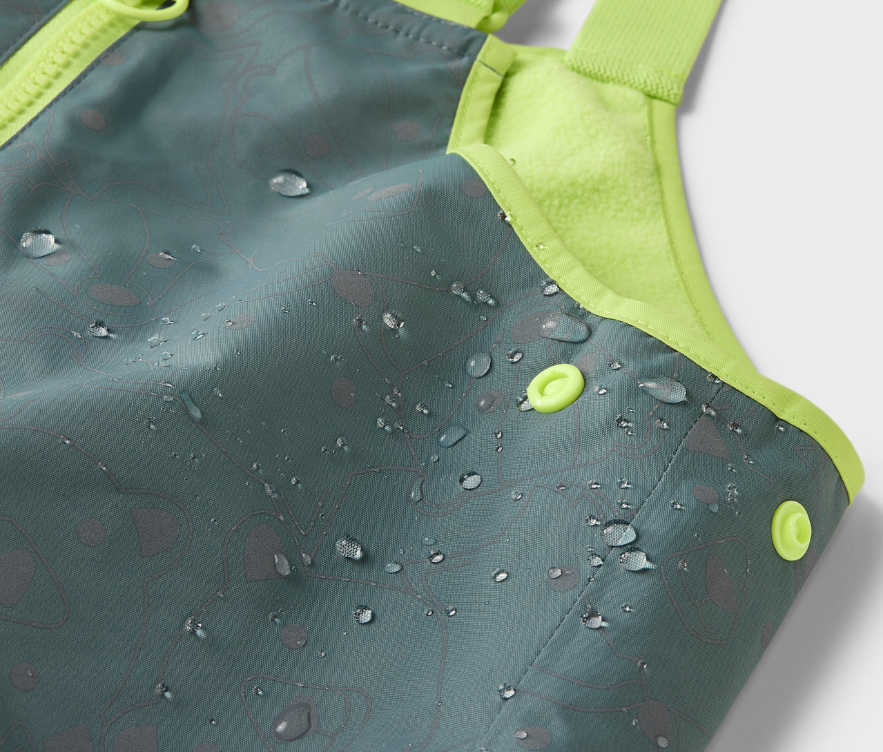 Detailaufnahme einer Kinder-Thermo-Regenhose mit reflektierenden Elementen, auf der Oberfläche sind Wassertropfen.