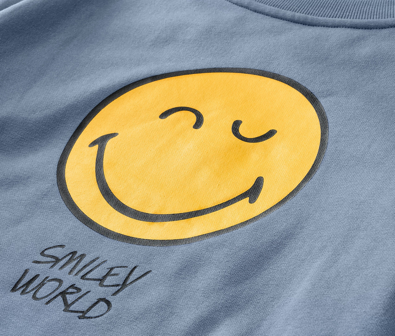 Detailaufnahme eines blauen Kinder-Sweatshirts SMILEYWORLD® mit gelbem Smiley.