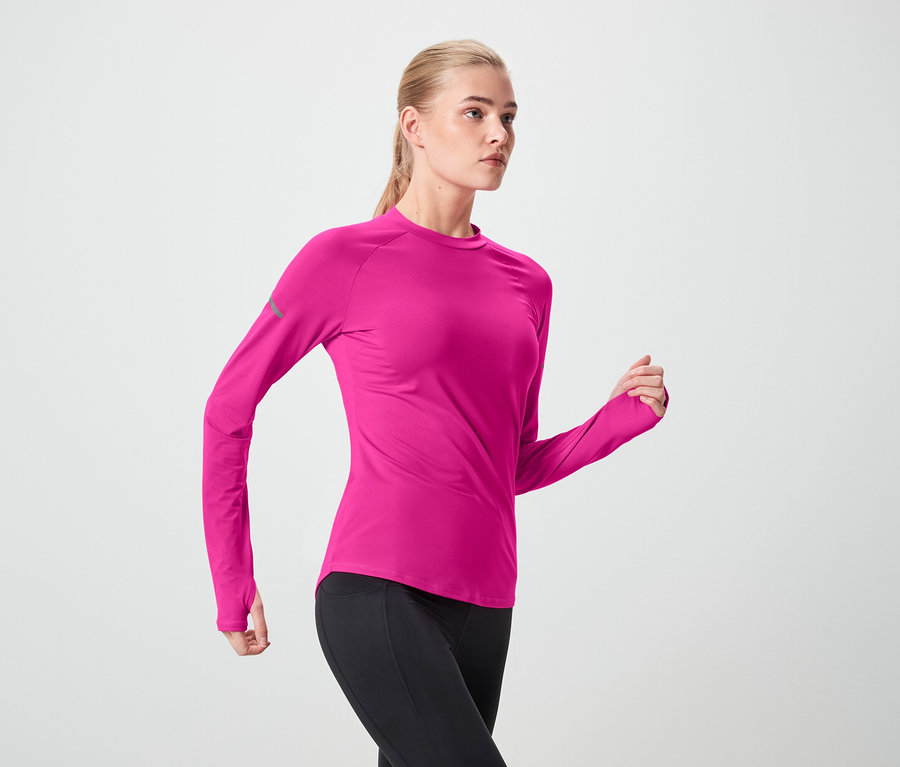 Frau in pinkem Sportoberteil und schwarzen Leggings in Bewegung.