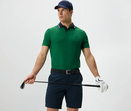 Mann hält Golfschläger und trägt ein grünes Funktions-Poloshirt.