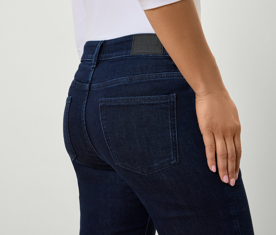 Detailansicht der Rückseite einer Frau, die eng anliegende blaue Jeans trägt.