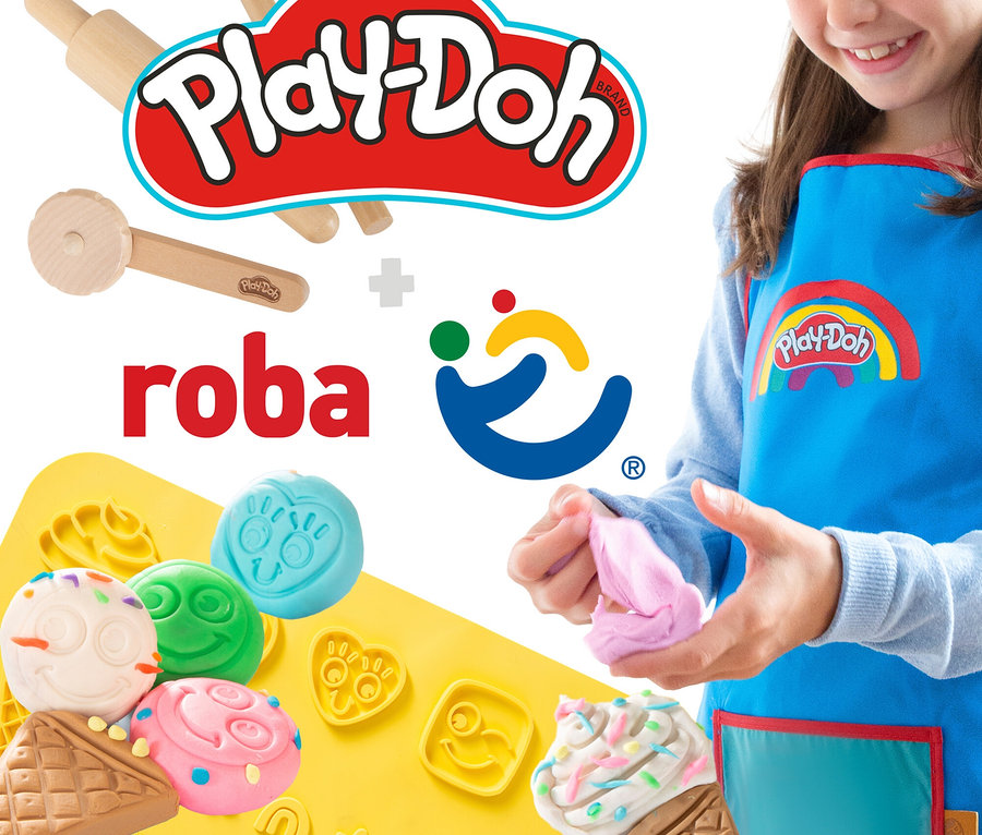 Ein Mädchen spielt mit Play-Doh Knete und formt Figuren auf einer gelben Unterlage. Sie trägt eine blaue Play-Doh Schürze.