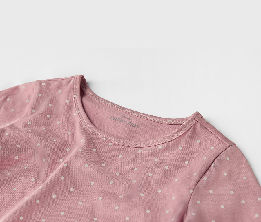 Nahaufnahme eines rosa "HAPPY KIDS" T-Shirts mit weißen Punkten.