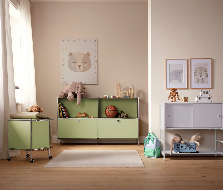 Ein Kinderzimmer mit hellgrünen und weißen Aufbewahrungsschränken, Spielzeug und Bildern an der Wand.