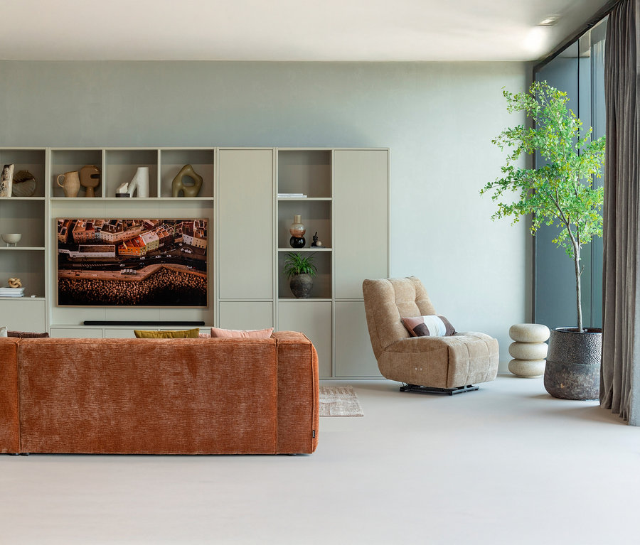 Wohnzimmer mit orangefarbenem Sofa, Sessel, Regalwand und Zimmerpflanze.