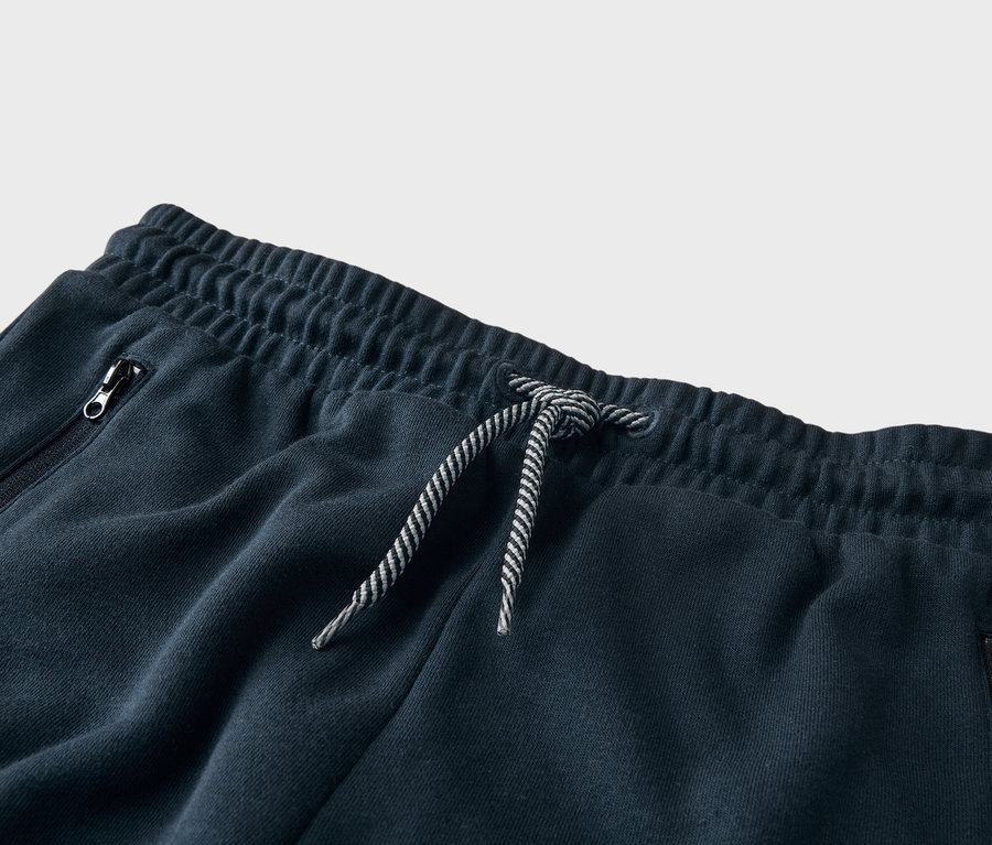 Nahaufnahme einer marineblauen Trainingshose mit Kordelzug und Reissverschlusstasche.