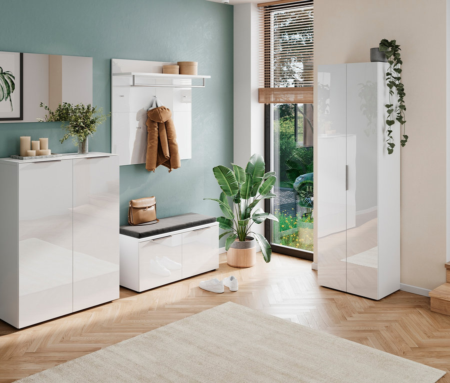 Eingangsbereich mit weißen Möbeln, darunter Schuhschrank, Garderobe und Bank, sowie Pflanzen und Deko.