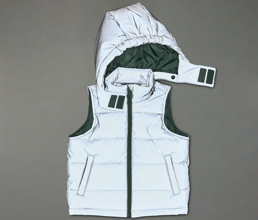 Reflektierende, ärmellose Pufferjacke mit Kapuze und grüner Innenseite liegt auf grauem Hintergrund.