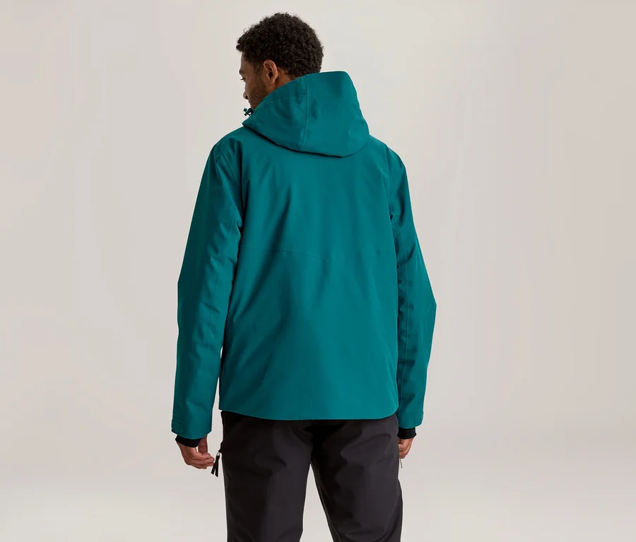 Mann von hinten, trägt eine türkise Kapuzenjacke und schwarze Hose, blickt leicht nach rechts.