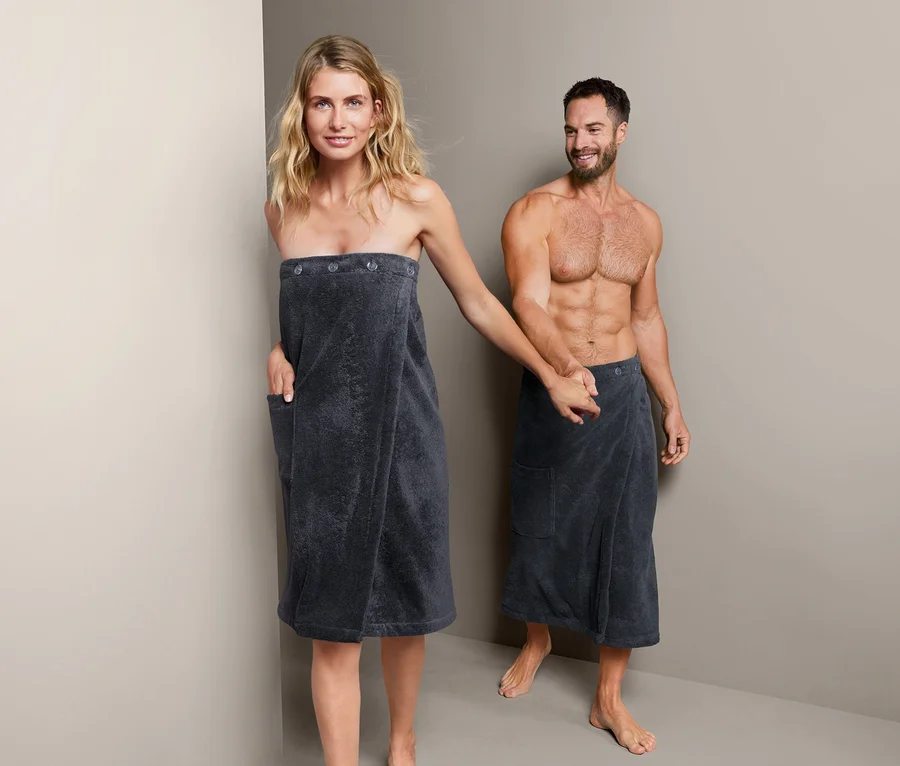 Frau und Mann halten Händchen, beide tragen einen Unisex-Sauna-Kilt.