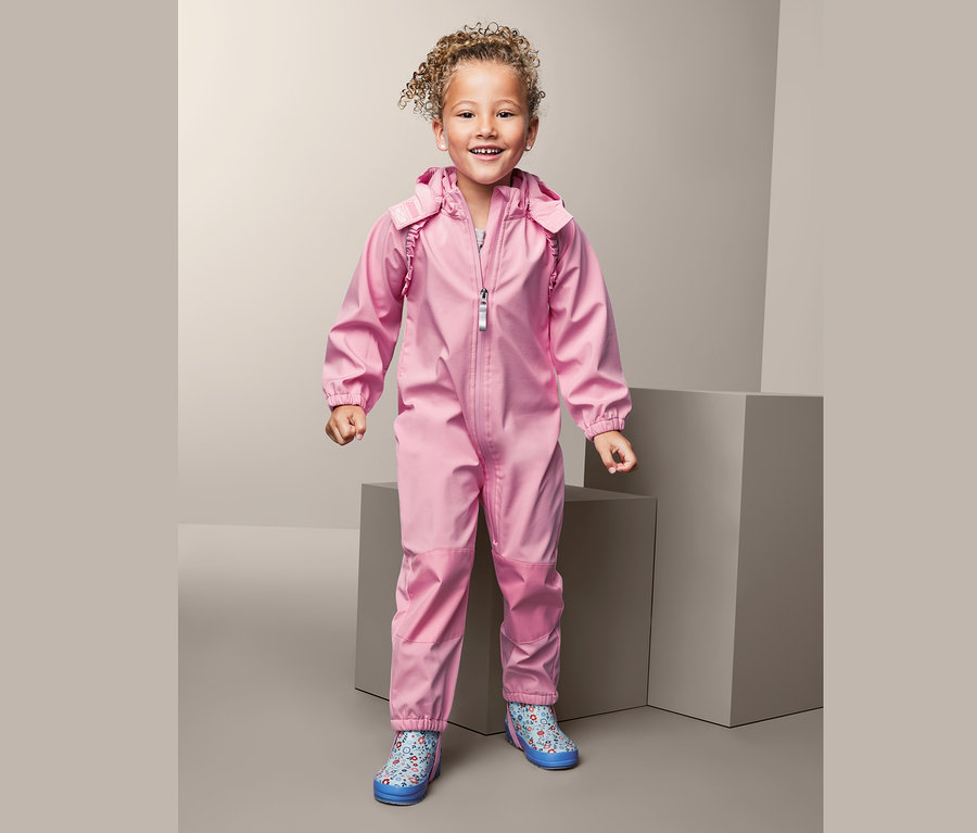 Lächelndes Mädchen im rosafarbenen Softshell-Einteiler aus recyceltem Material.