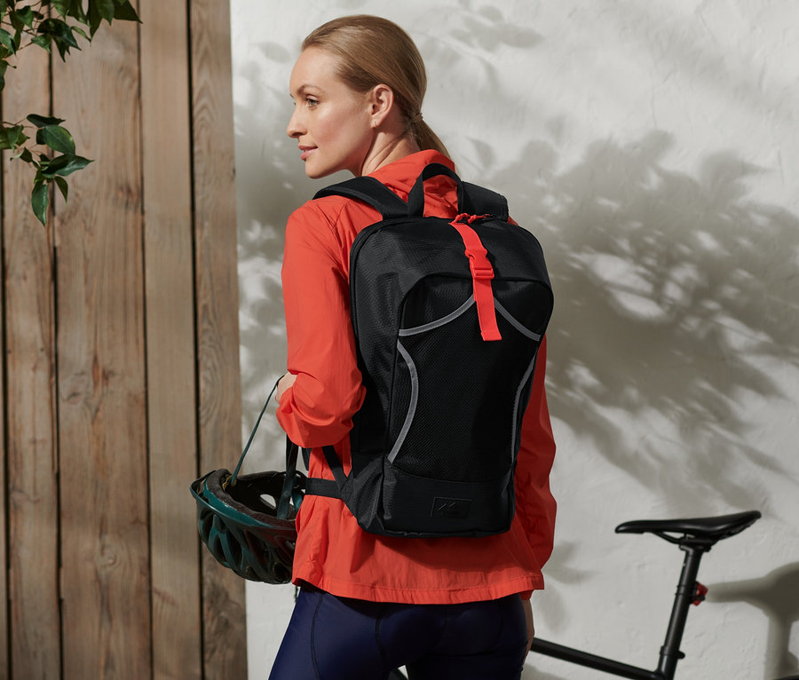 Frau trägt einen Fahrrad-Rucksack und hält einen Helm.