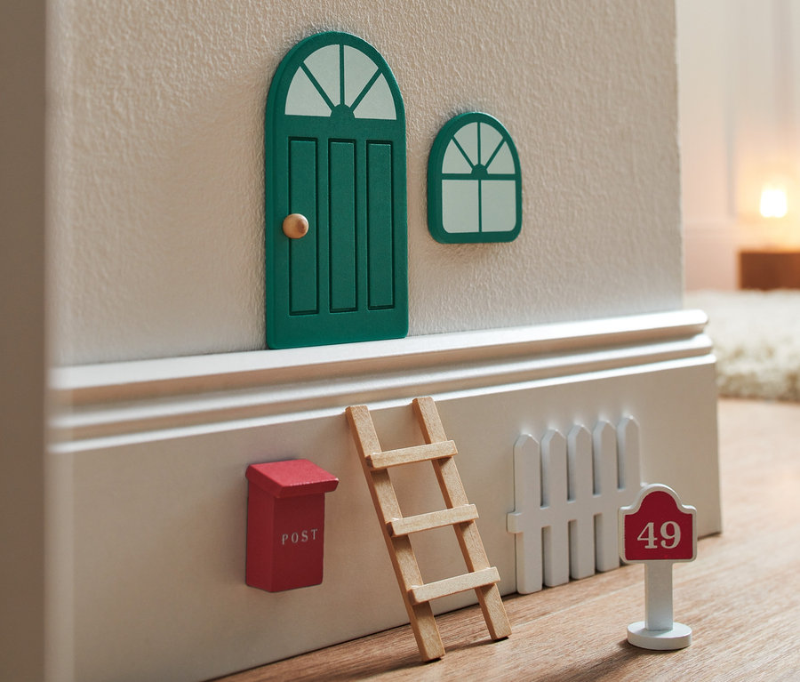 Ein Wichteltür-Set mit einer geschlossenen grünen Tür, einem Fenster, einem roten Briefkasten, einer Leiter und einem weißen Zaun mit der Hausnummer 49.