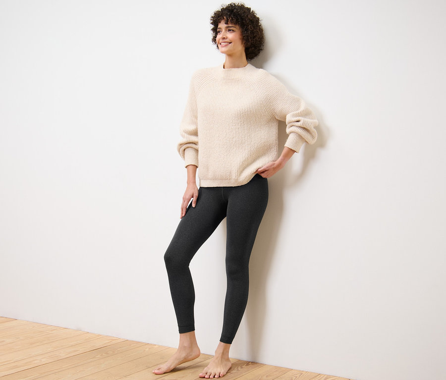 Frau posiert in gefütterten Leggings und Pullover.