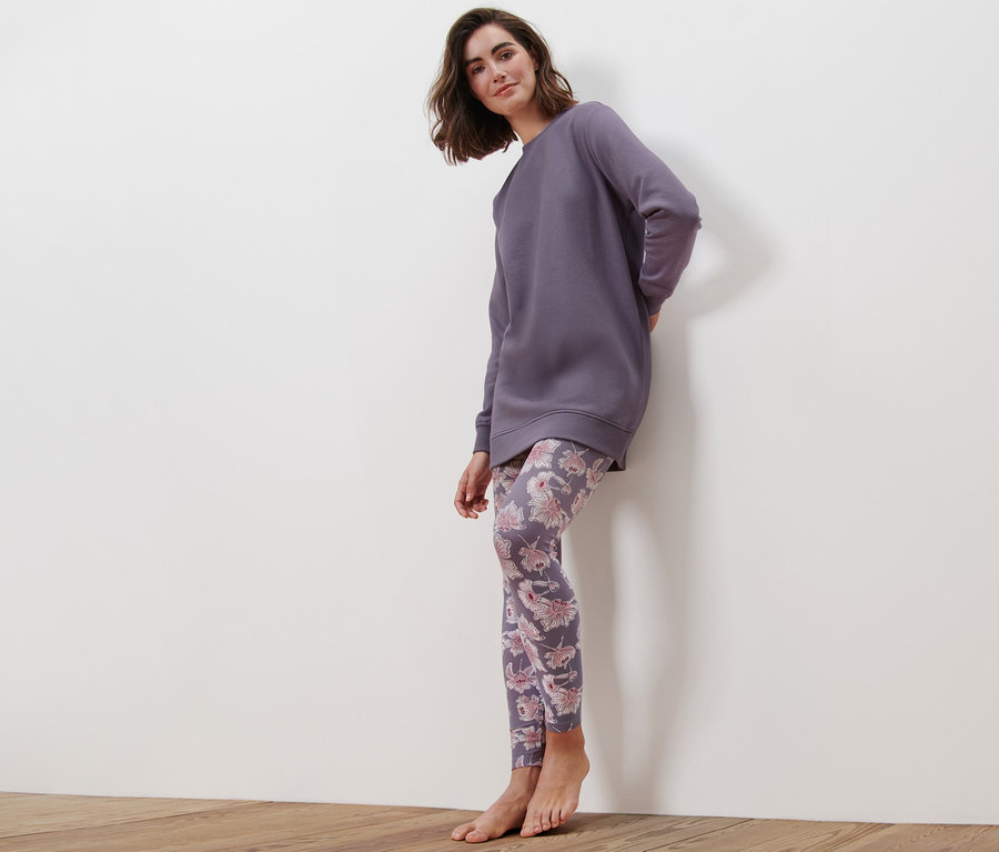 Frau im Pyjama lehnt an der Wand.