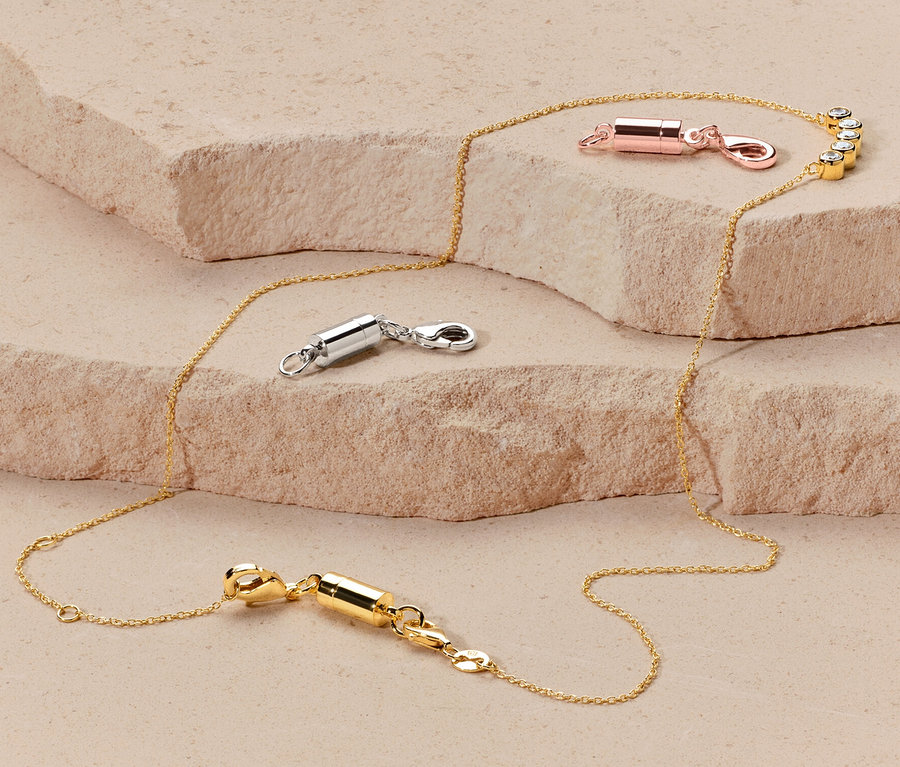 Goldkette mit Magnetverschluss-Set in Roségold, Silber und Gold liegt auf einem Hintergrund.