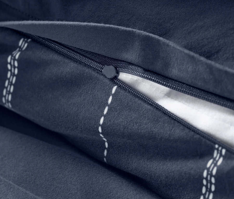 Detailansicht eines Reißverschlusses und Streifenmusters auf marineblauer Winterjersey-Bettwäsche.