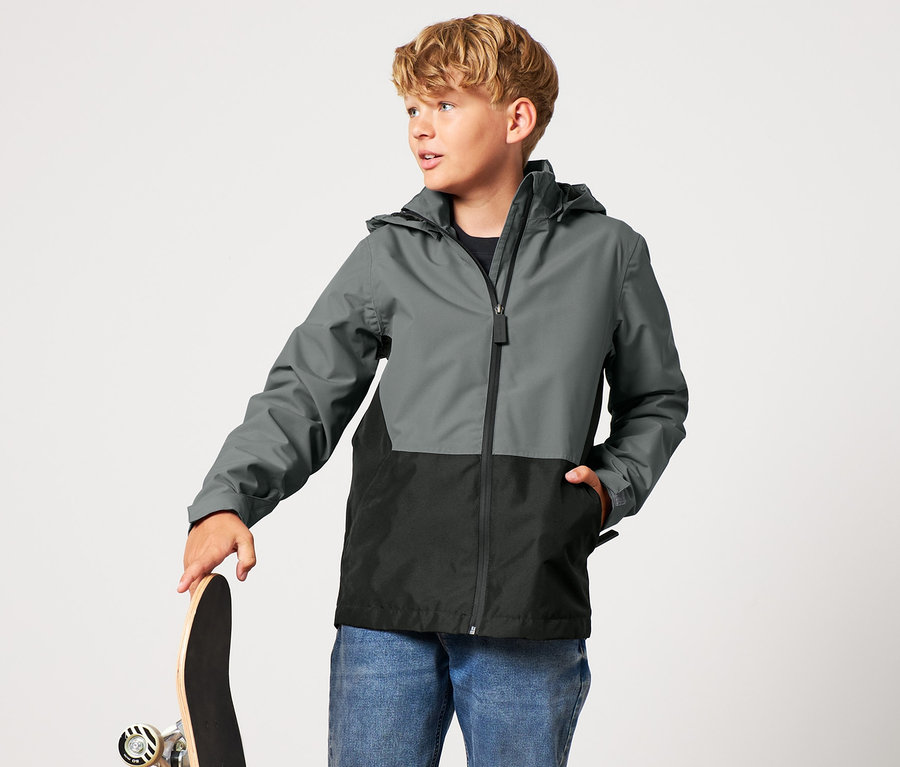 Junge mit Kinder-Regenjacke hält ein Skateboard.