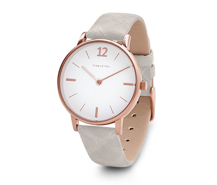 Nahaufnahme einer Armbanduhr mit Lederband, weißem Zifferblatt und roségoldenem Gehäuse.