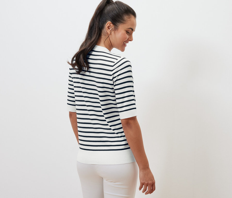 Frau steht mit dem Rücken zur Kamera und trägt einen navy gestreiften Feinstrickpullover.