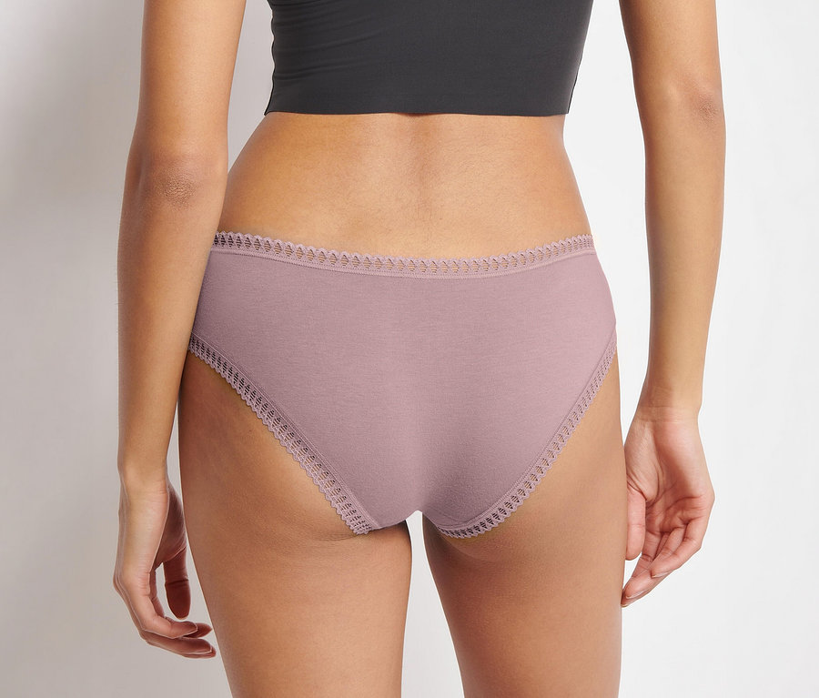 Rückenansicht einer Person, die einen schwarzen Crop-Top und einen rosafarbenen sloggi GO Crush Hipster C3P Slip mit Spitzenbesatz trägt.