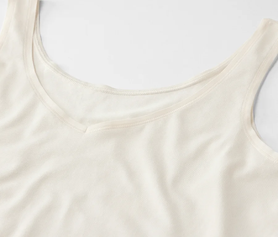 Detailansicht eines cremefarbenen Tanktops mit V-Ausschnitt.