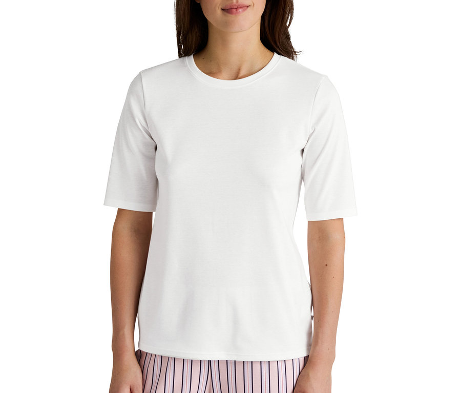 Frau trägt ein weißes T-Shirt mit kurzen Ärmeln und eine gestreifte Pyjamahose.