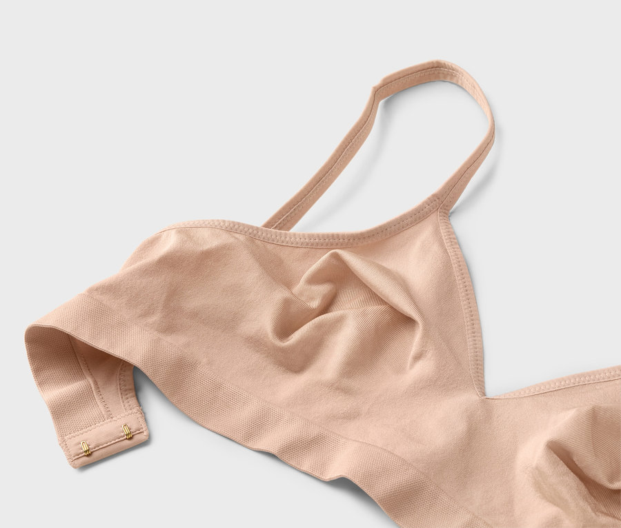 Nahaufnahme eines hautfarbenen BHs mit dünnen Trägern und goldenen Haken.